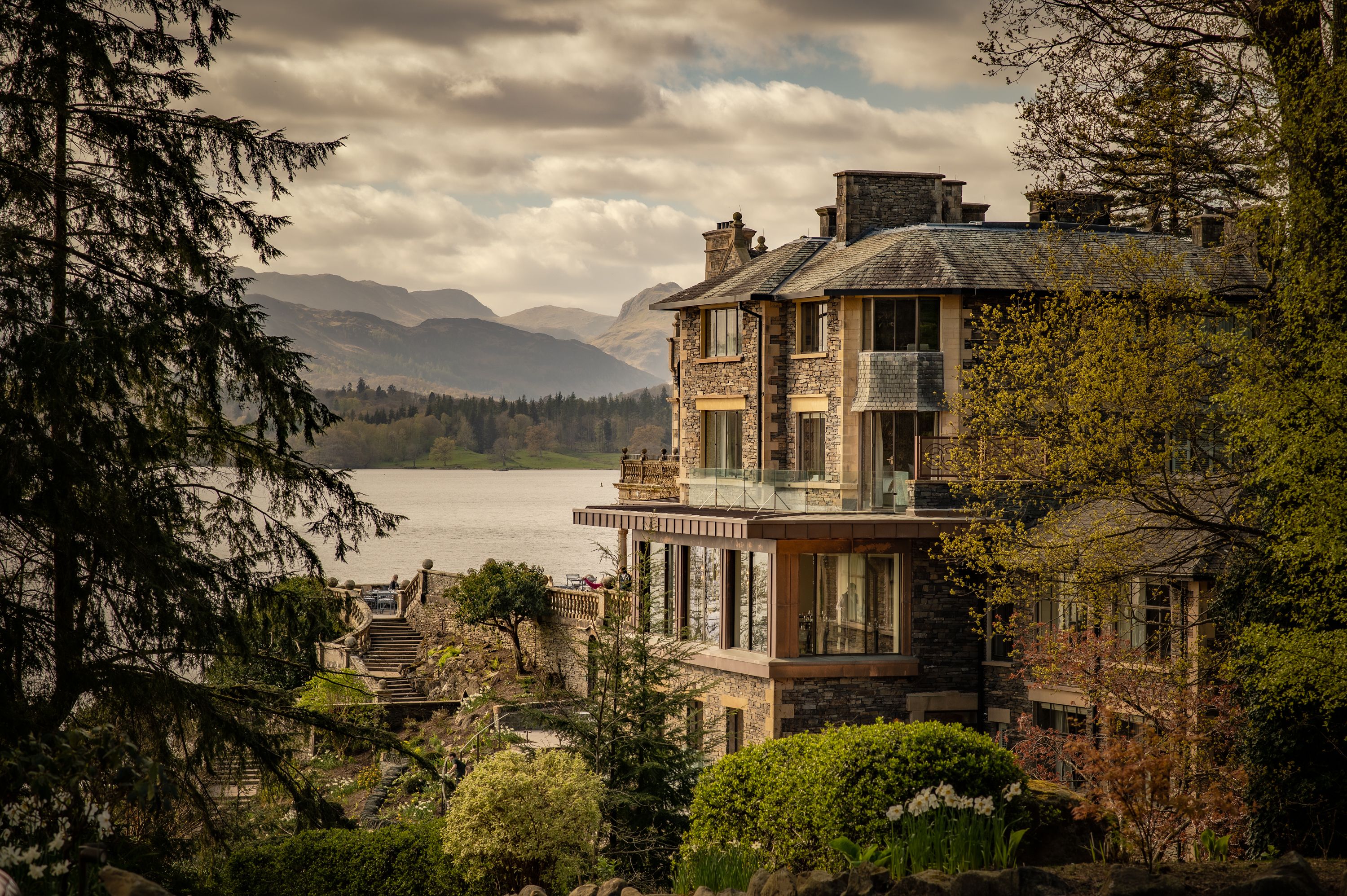 stone mansion on a hill overlooking a lake